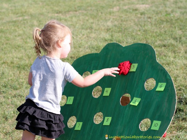 Play an apple tree gross motor game to get kids moving and practicing numbers. Homemade yarn apples add a special touch.