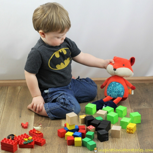toddler stacking blocks with a toy fox