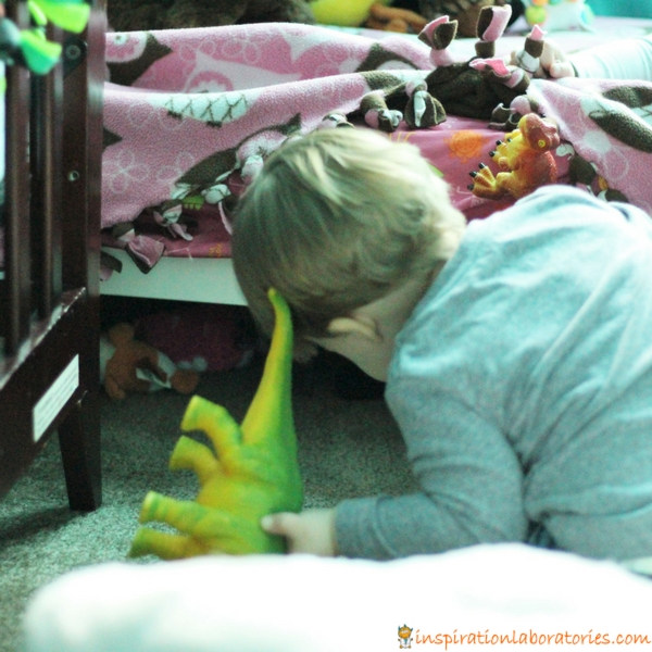 toddler looking under bed for dinosaur toy