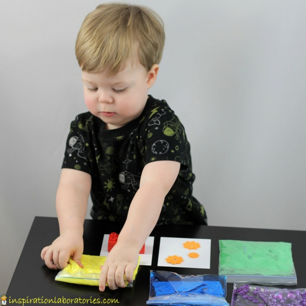 toddler touching bag filled with yellow oobleck