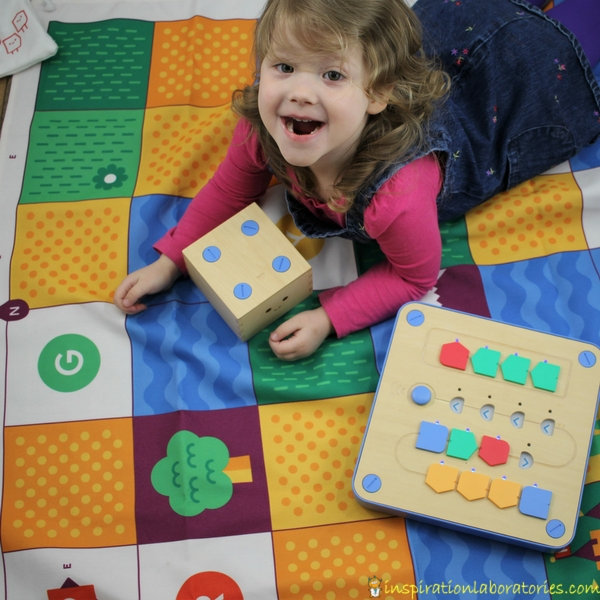 preschool girl with Cubetto, a wooden cube robot 
