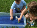 Set up a simple ocean sensory bin with colored sand and water.