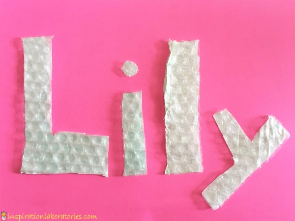 "Lily" cut out of bubble wrap on pink paper