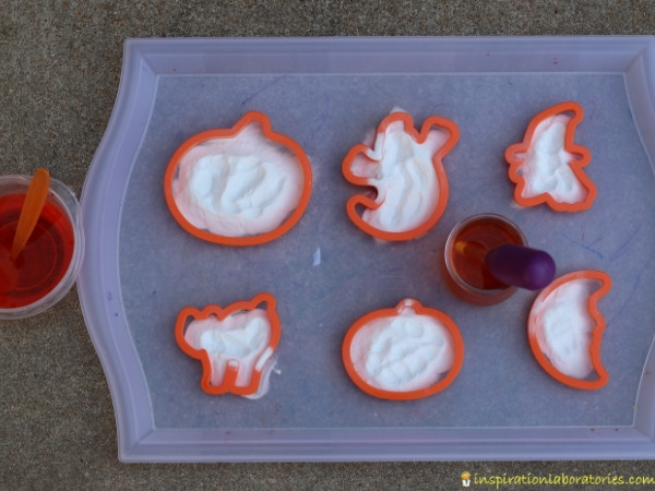 Halloween cookie cutters and baking soda on tray with vinegar
