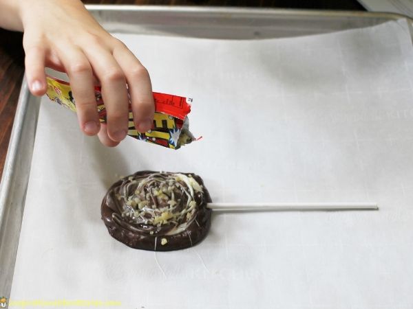 adding popping candy to chocolate lollipop