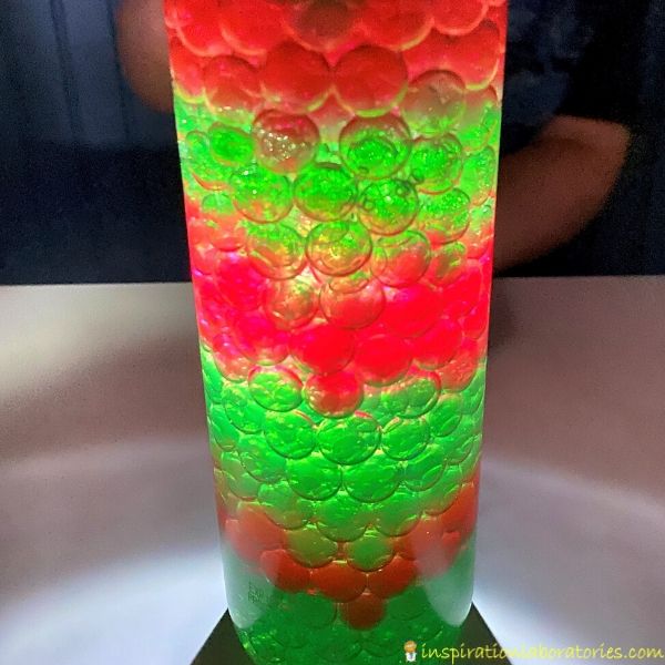 flashlight shining through Christmas sensory bottle with oil and water beads