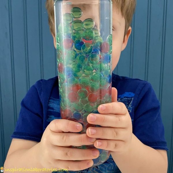 child watching the water beads fall in a sensory bottle