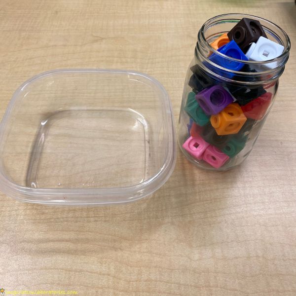 a small jar with colorful math link cubes next to an empty square container